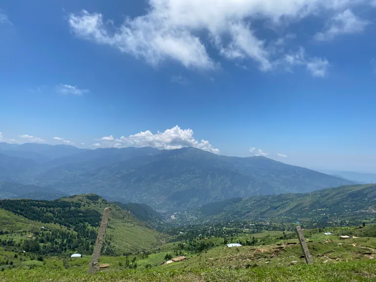 Rolling green slopes at Nathatop with blue mountain ranges in the distance